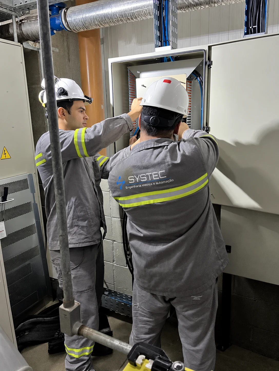 Equipe Systec durante uma intervenção no interior de um painel elétrico.