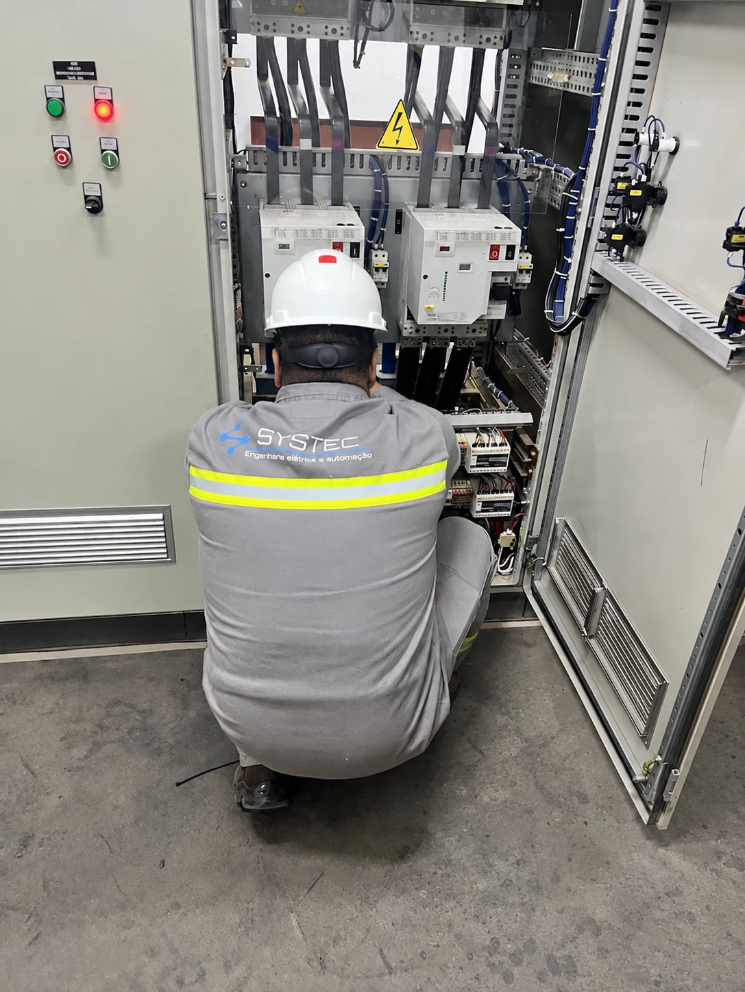Técnico Systec trabalhando no interior de um painel elétrico industrial.