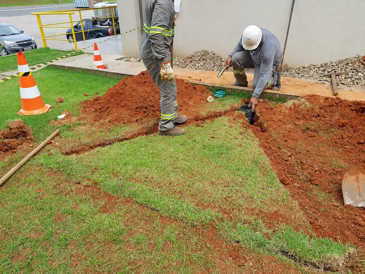 Equipe em atividade junto à caixa de inspeção, na frente de serviço.