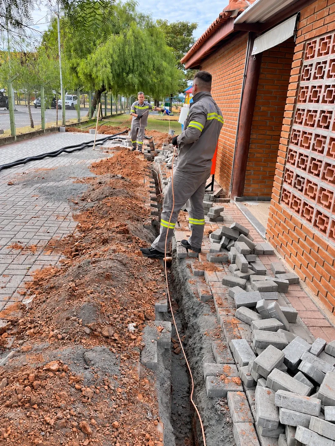 Condutor ao longo da vala, com equipe na frente de serviço.